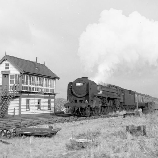 A Britannia class Pacific powers a rugby football special from Glasgow to Cardiff over the A666 road bridge and past the former Langho signalbox. The site of the former Langho goods yard is in the foreground.
